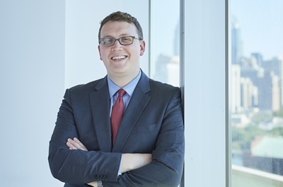 Plastic surgeon Dr. John Fischer leaning against wall